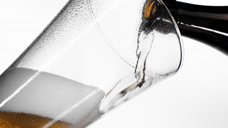 Close-up-background-of-pouring-beer-with-bubbles-and-foam-in-glass-low-angle-side-view-slow-motion